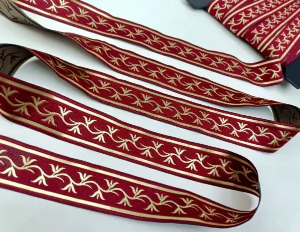 gerade-ausgelegtes-zierband-mit-rot-hintergrund-und-gold-gesticktem-rankenmuster-auf-transparentem-netzstoff-hintergrund
